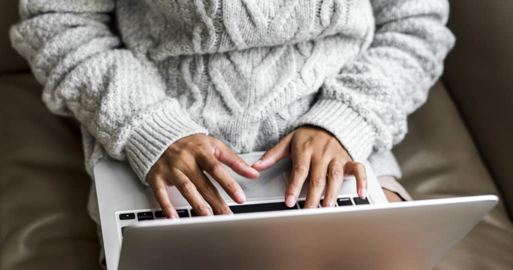 Woman in cosy cable jumper working on laptop